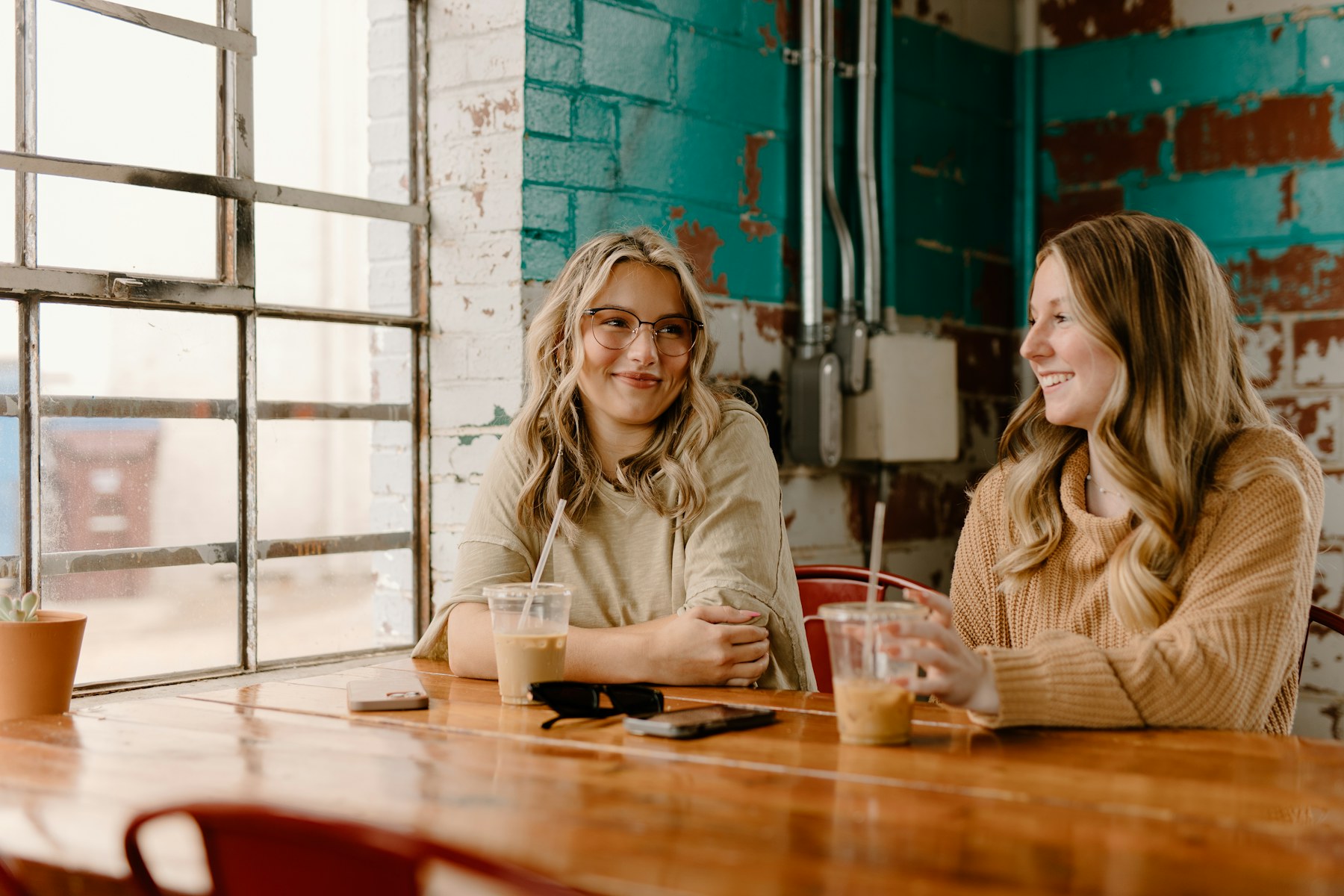 Two people talking closely over coffee in a bright café